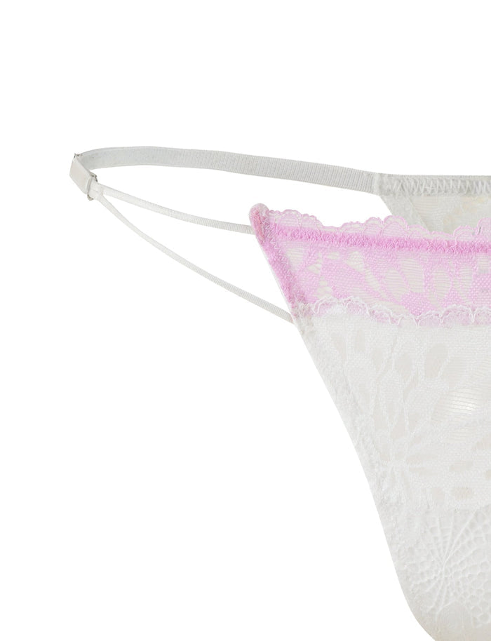 Close-up of the TIGERMIST DEVYN SET - MULTI in white and pink, featuring a lace bikini-style lingerie with a white base and pink trim. The image highlights the side details, including thin white elastic straps, intricate lace patterns, and adjustable shoulder straps. This elegant piece is ideal for pairing with the matching bra and g-string for a complete look.
