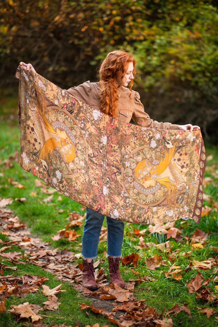 Model wearing Dreamweaver Zodiac Scarf – featuring Alphonse Mucha’s 1896 celestial woman surrounded by zodiac signs and floral scroll artwork – Market of Stars.