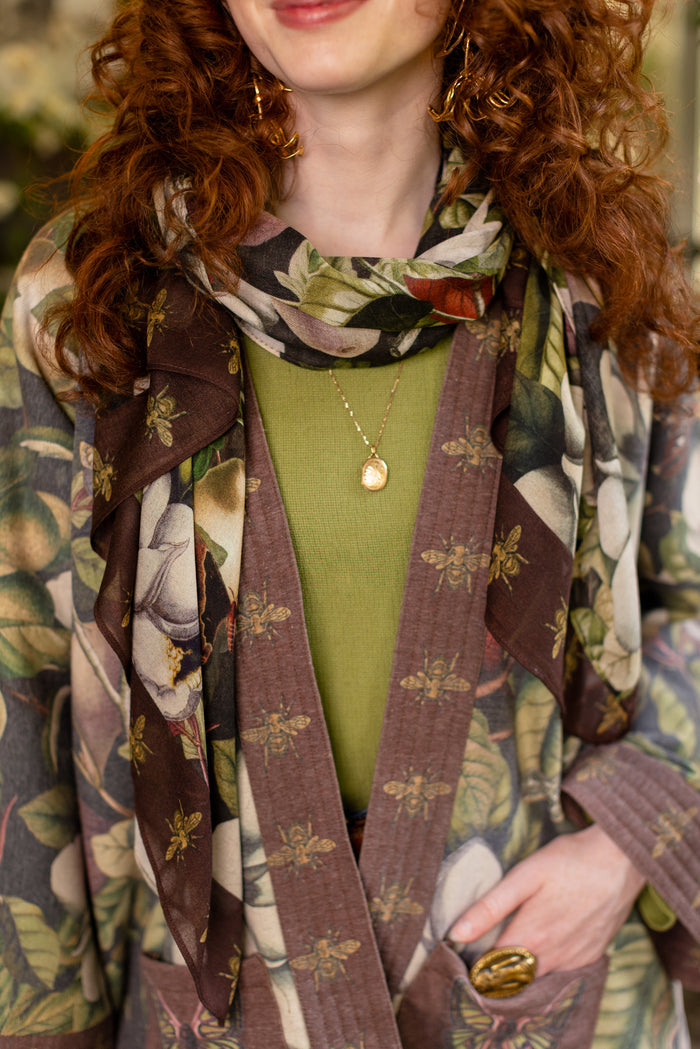 Model wearing a lightweight bamboo viscose scarf featuring vintage magnolia lithographs, delicate moth etchings and charming bumblebee trim - Market of Stars