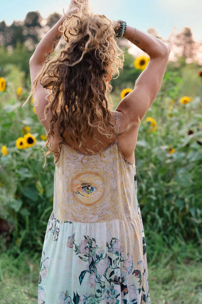 Model wearing bamboo viscose slip dress featuring Van Gogh artwork and quote, with painted blossoms, book, sun, and eye in rich sunny tones of jade and gold - Market of Stars