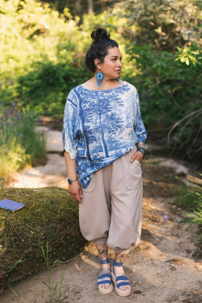 Model wearing Let the Light In bamboo viscose Luxe Tee shirt featuring print of Delft blue and white landscape pottery, and positive message of light and hope - Market of Stars