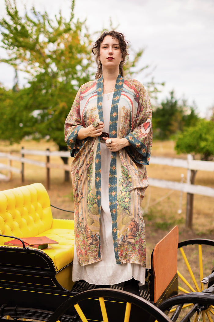 Model wearing a full-length duster ft. a woman astride a rearing horse, soft vintage florals, rosettes and lithographs from the 1800's - Market of Stars
