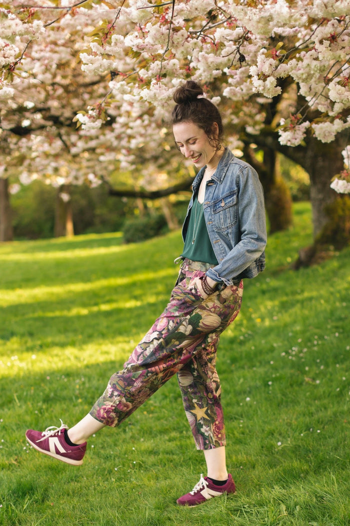 Model wearing linen blend artist pants featuring antique wishbone–Victorian coin–evening star–dandelion art and “Wish with Me” banner on floral background – Market of Stars