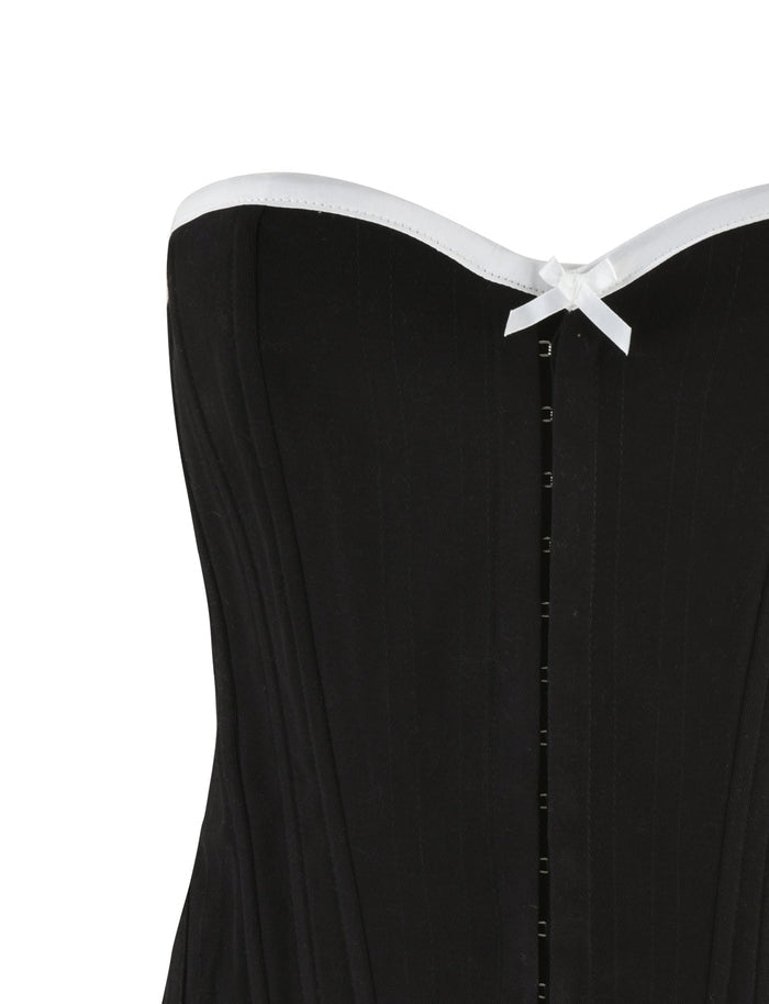 A close-up of the top part of the MILLIE CORSET 2.0 - BLACK by TIGERMIST, featuring a strapless design with white trim along the top edge. The corset includes a small white bow in the center near the top, vertical boning for structure, and a lace-up back for an adjustable fit.