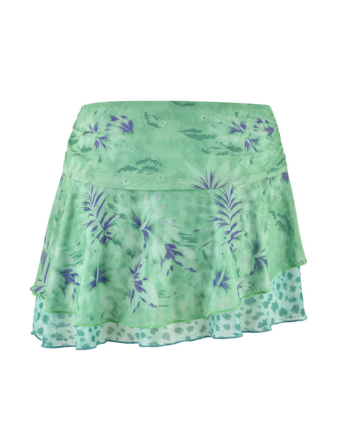 The SAIGE SKIRT by TIGERMIST is made from a high stretch fabric in light green, featuring floral accents with purple and white flowers and subtly integrated animal print. The multiple layers of the skirt provide a flowy and textured look.