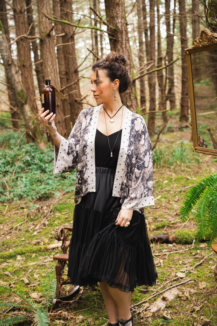 Model wearing Looking Glass Cropped Kimono featuring grown-up Alice Liddell, rare Victorian botanicals, and celestial star and moon accents inspired by Wonderland – Market of Stars.