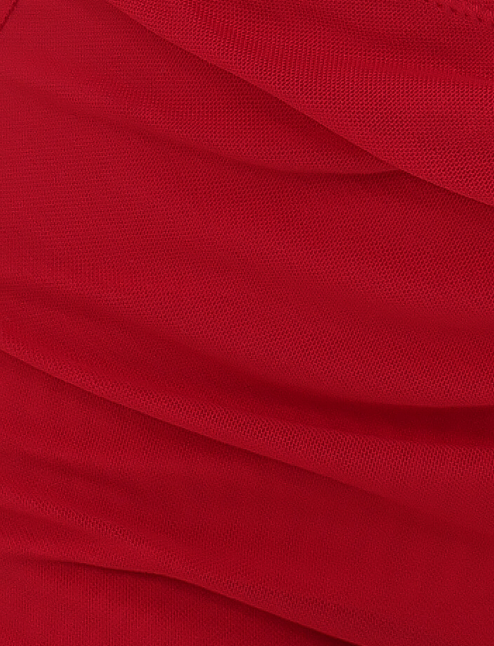 Close-up of ZAFIRA SHORT - RED by TIGERMIST, featuring a bright red hue with a textured weave and folds, forming diagonal lines and soft shadows on the high-stretch fabric.