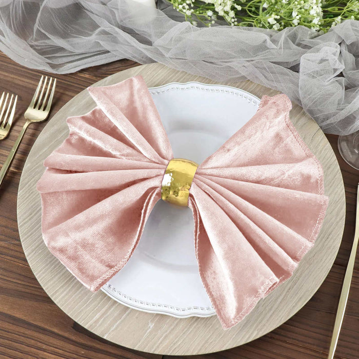 Elegant pink velvet napkin with gold ring on a white plate.