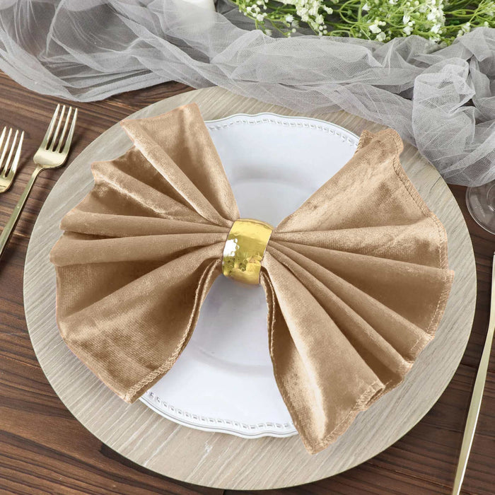 Elegant gold napkin ring with satin napkin on a decorative plate.