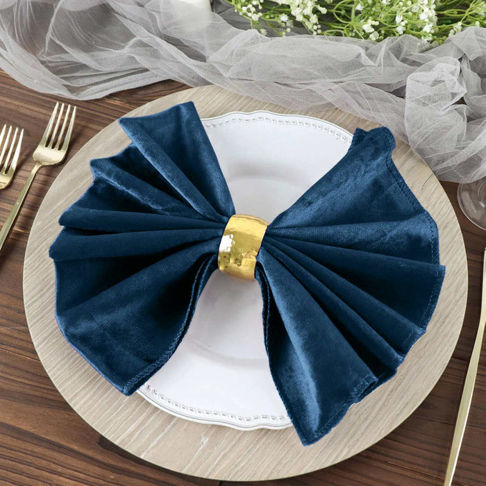 Navy blue velvet napkin with gold ring on a decorative plate.