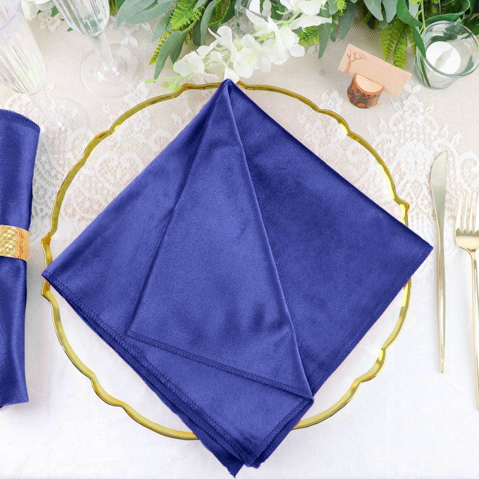 Navy blue cloth napkin on a decorative gold plate.