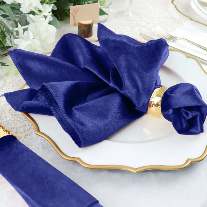 Navy blue satin napkin elegantly folded on a decorative plate.