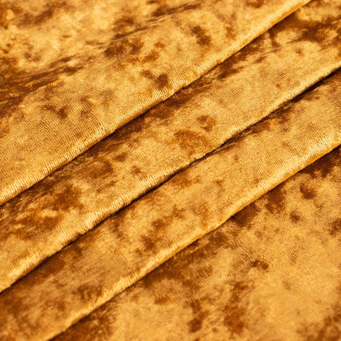 Golden brown velvet fabric close-up with pleated texture and mottled pattern