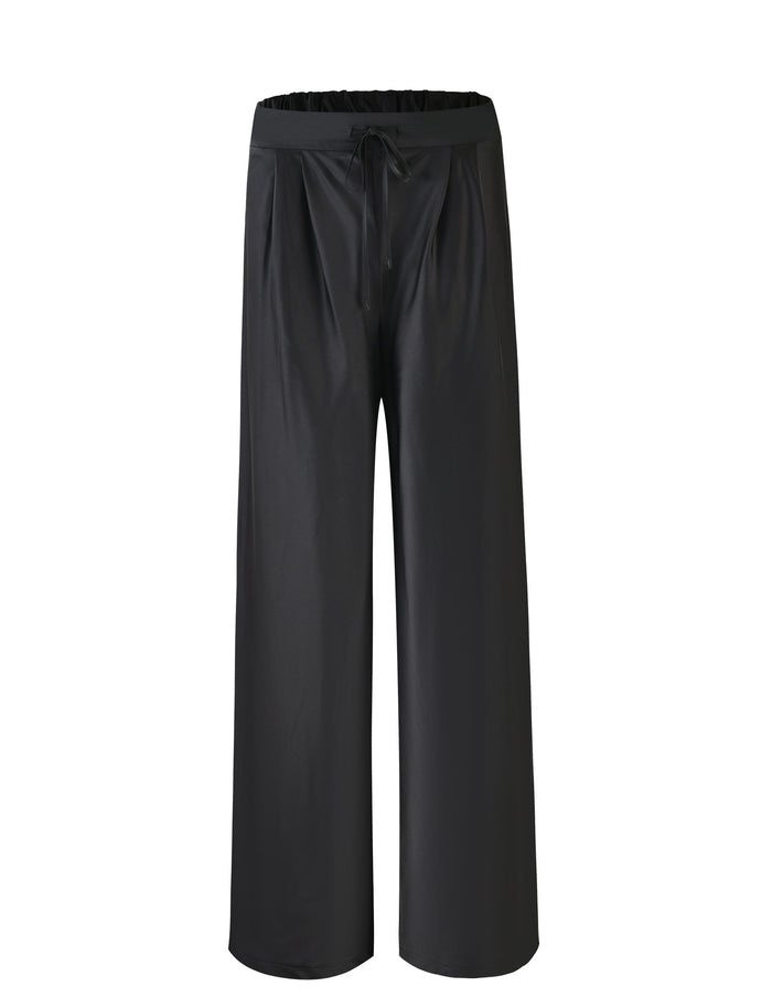 The ALINA PANT - BLACK from TIGERMIST features an elastic waistband and a drawstring tie at the front. The fabric appears sleek and flowy, with subtle pleats at the top.