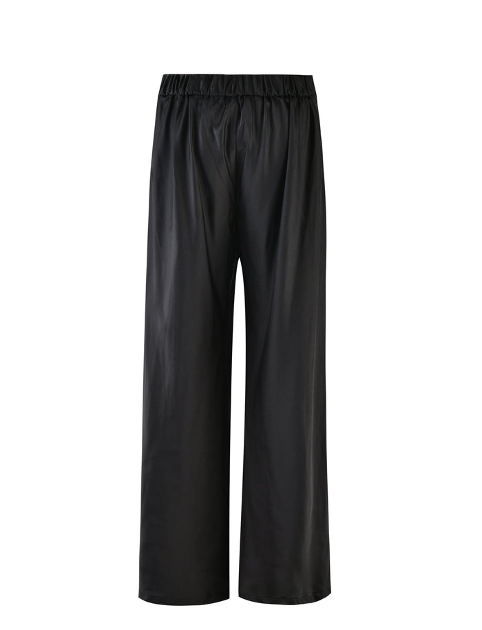 The ALINA PANT - BLACK from TIGERMIST are a stylish pair of black wide-leg pants featuring an elastic waistband. The fabric has a smooth and slightly shiny finish, giving these pants a sleek appearance. They offer a loose, flowing fit that makes them versatile for both casual and semi-formal occasions. The background is plain white.