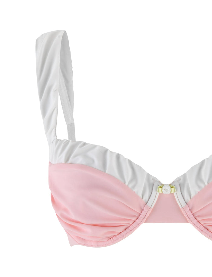 The AMARAN BIKINI TOP in pastel pink by TIGERMIST features ruched detailing, adjustable shoulder straps, and a small decorative bow at the center, reminiscent of a bodycon fit. Displayed on a white background, this bikini top offers both style and comfort.