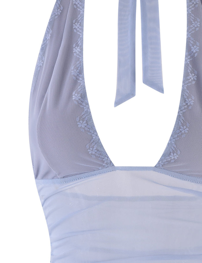 The TIGERMIST BRESILY TOP - STEEL BLUE offers a detailed look with its lace-trimmed halter top in a stunning steel blue shade, featuring sheer sections. The fabric highlights an intricate embroidered design along the neckline, showcasing delicate detailing.