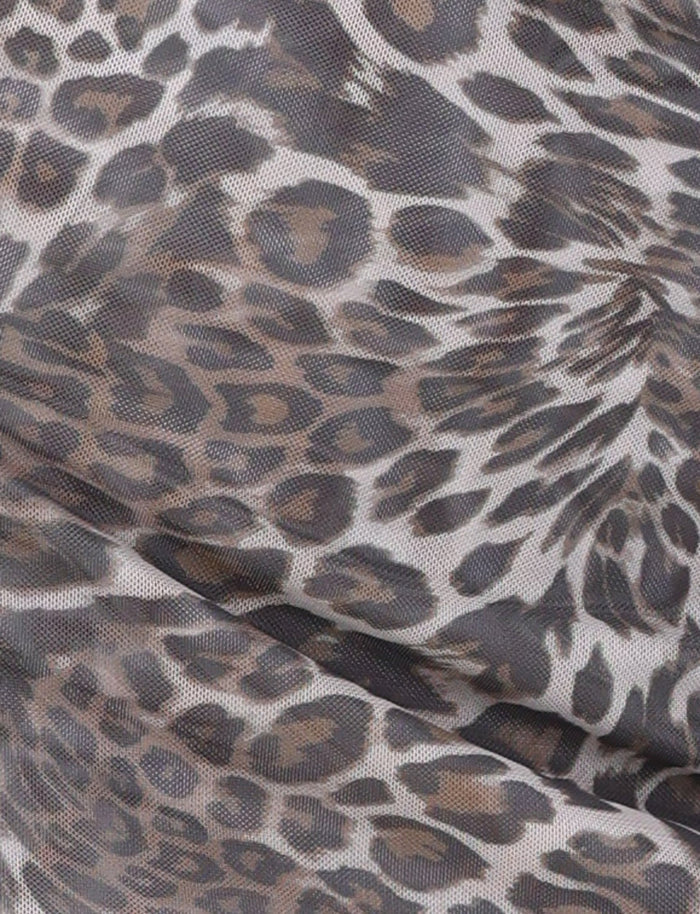 Close-up of the CAMPBELL MINI DRESS - NEUTRAL: LEOPARD by TIGERMIST, showcasing its high-stretch fabric with a leopard print pattern. The design features spots in shades of brown and black on a light beige background. The fabric appears to be slightly gathered, exhibiting a mesh-like texture.