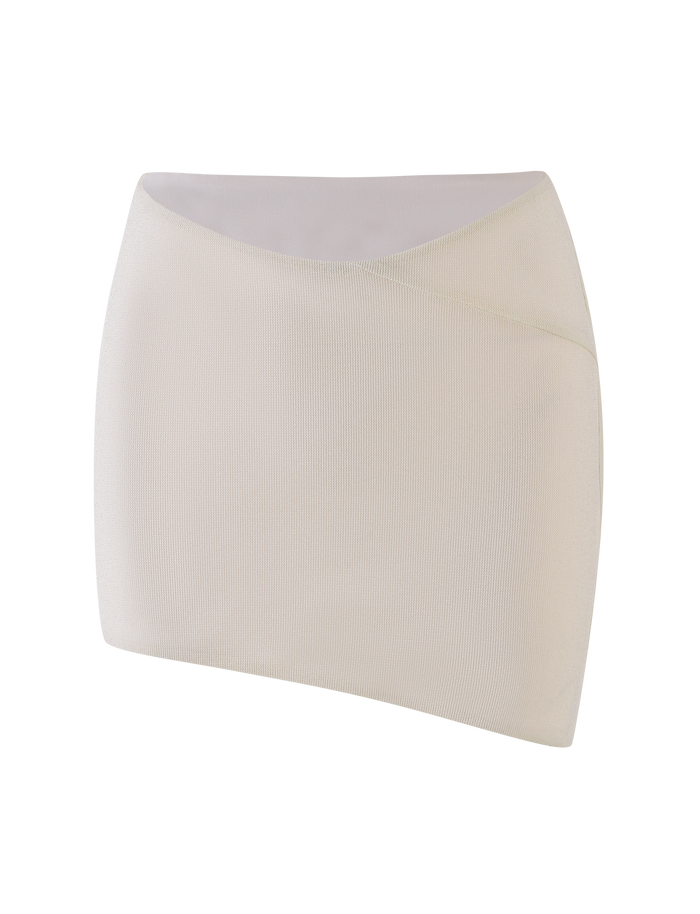 The TIGERMIST COBI SKIRT - WHITE : CREAM is a ribbed, asymmetrical mini skirt with a diagonal waistband in shimmer jersey, shown on a plain white background.