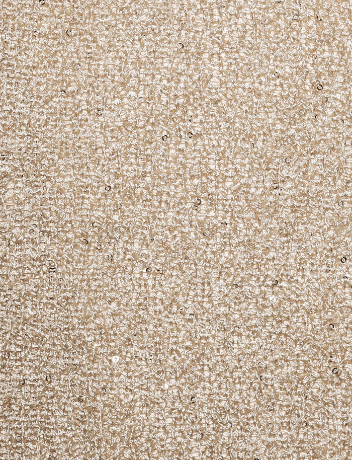 Close-up shot of the TIGERMIST CONNELL SKIRT - GOLD. The fabric features a textured beige surface with a rough, woven pattern and small specks of darker brown interspersed throughout, reminiscent of intricate knit fabrication that provides a tactile and visually engaging appearance.