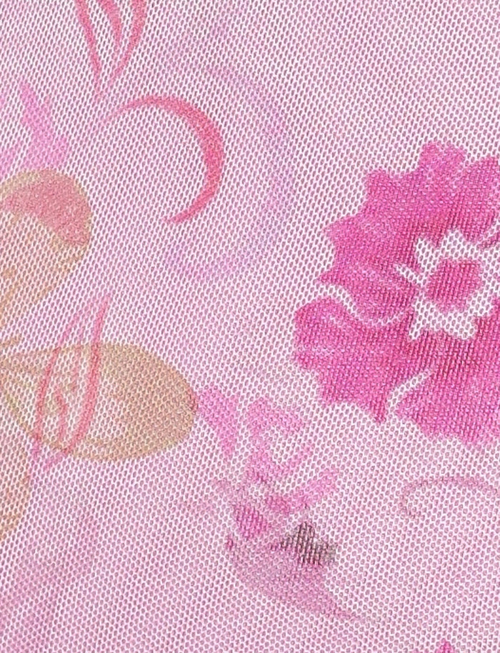 A close-up of the TIGERMIST COSETTE DRESS - PINK : DELICATE FLORAL showcases the textured pink fabric adorned with floral patterns in shades of pink and beige. The mesh fabrication adds a layered effect, making it ideal for creating a breezy dress or a versatile halter neckline design.