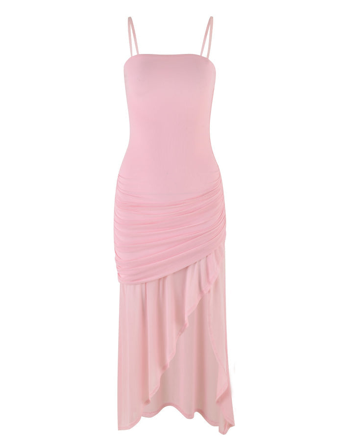 The COVE DRESS - PINK in Baby Pink by TIGERMIST is a light pink sleeveless marvel with spaghetti straps and a fitted silhouette. It features ruched detailing around the hips and an asymmetrical, cascading hemline that creates a soft, flowing appearance. The fabric is smooth and flowy.