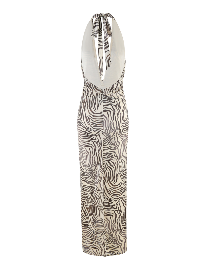 The CRESSIDA DRESS - NEUTRAL : ZEBRA by TIGERMIST is a sleeveless, floor-length halter neck dress with a zebra print, deep scoop neckline, open back, and straight silhouette, shown on a white background.