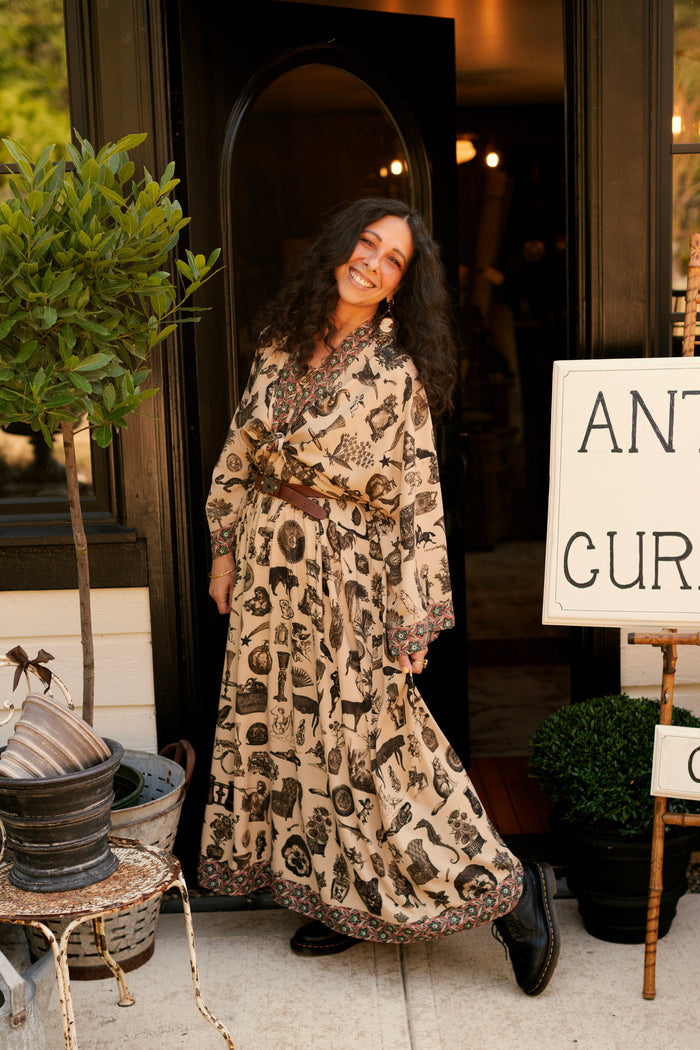 Model wearing a maxi-length bamboo viscose slip dress inspired by a mysterious Victorian scrapbook. This whimsical print celebrates the wonder hidden in ordinary things — Market of Stars.