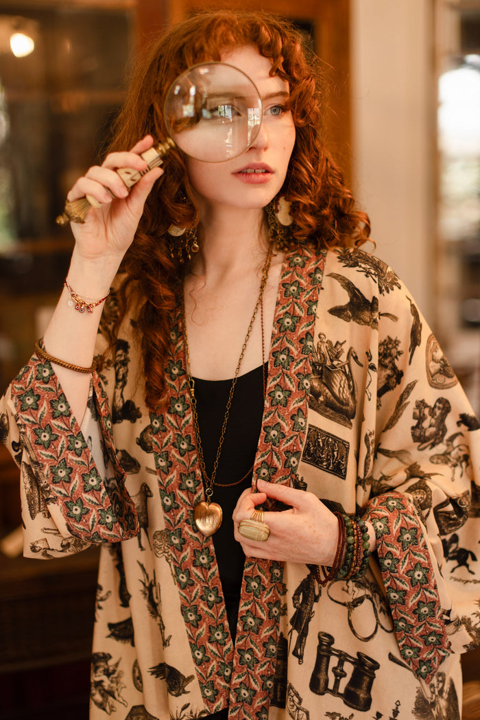 Model wearing a bamboo-viscose cropped length duster inspired by a mysterious Victorian scrapbook. This whimsical print celebrates the wonder hidden in ordinary things — Market of Stars.
