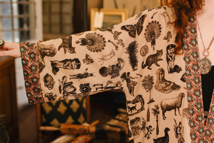 Model wearing a bamboo-viscose cropped length duster inspired by a mysterious Victorian scrapbook. This whimsical print celebrates the wonder hidden in ordinary things — Market of Stars.