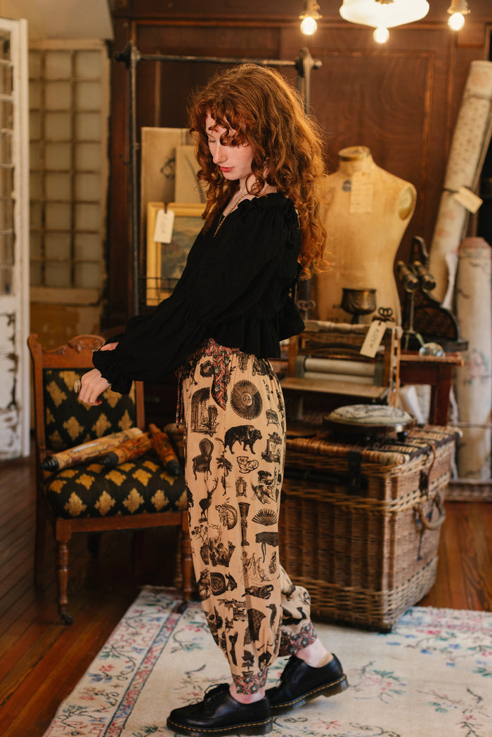 Model wearing relaxed viscose pant with elastic and drawstring waist, inspired by a mysterious Victorian scrapbook. This whimsical print celebrates the wonder hidden in ordinary things — Market of Stars.