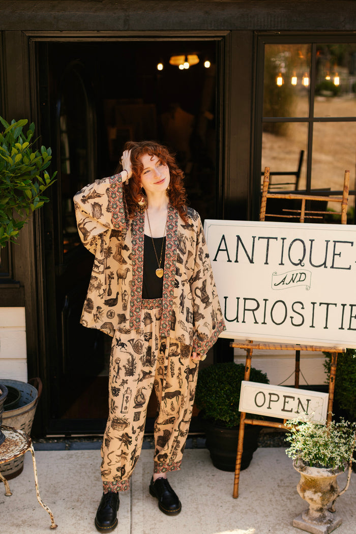 Model wearing relaxed viscose pant with elastic and drawstring waist, inspired by a mysterious Victorian scrapbook. This whimsical print celebrates the wonder hidden in ordinary things — Market of Stars.