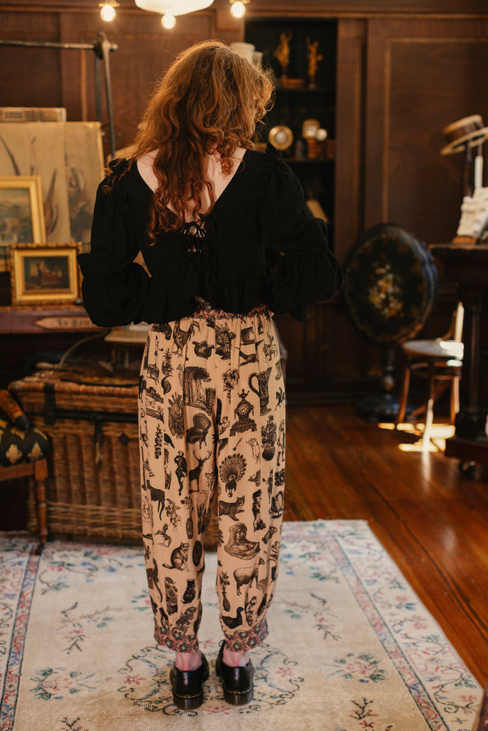 Model wearing relaxed viscose pant with elastic and drawstring waist, inspired by a mysterious Victorian scrapbook. This whimsical print celebrates the wonder hidden in ordinary things — Market of Stars.