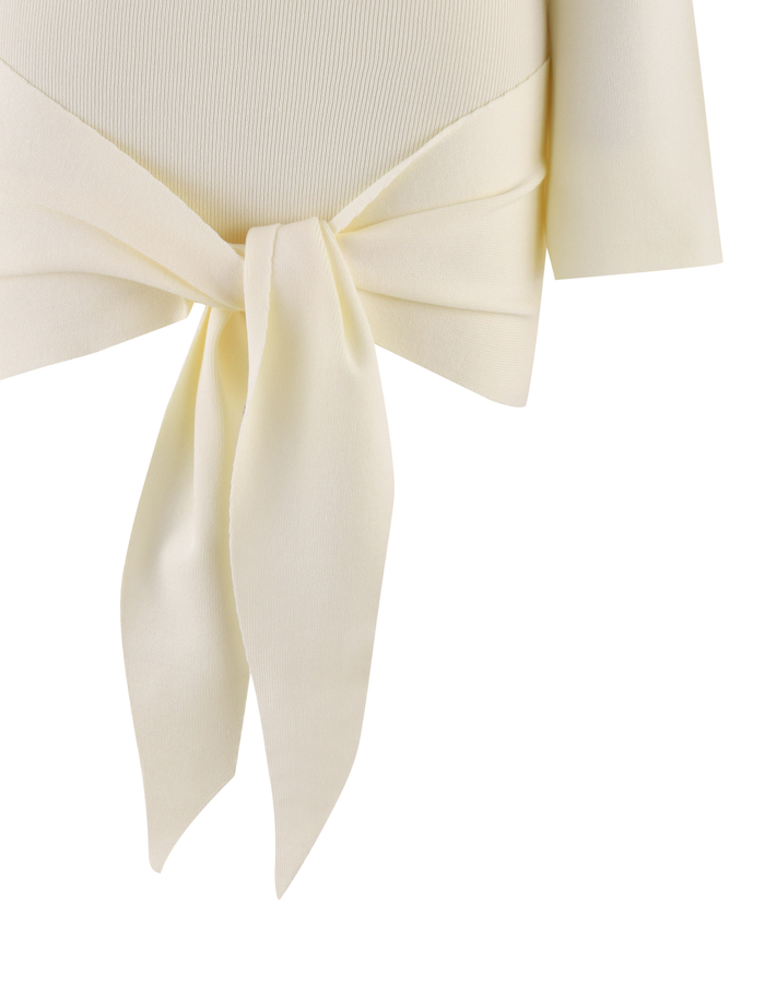 Close-up of the TIGERMIST CYPRESS DRESS in white/cream, featuring a neat waist bow with long pointed ends. The background is plain, highlighting the smooth yet slightly textured fabric.