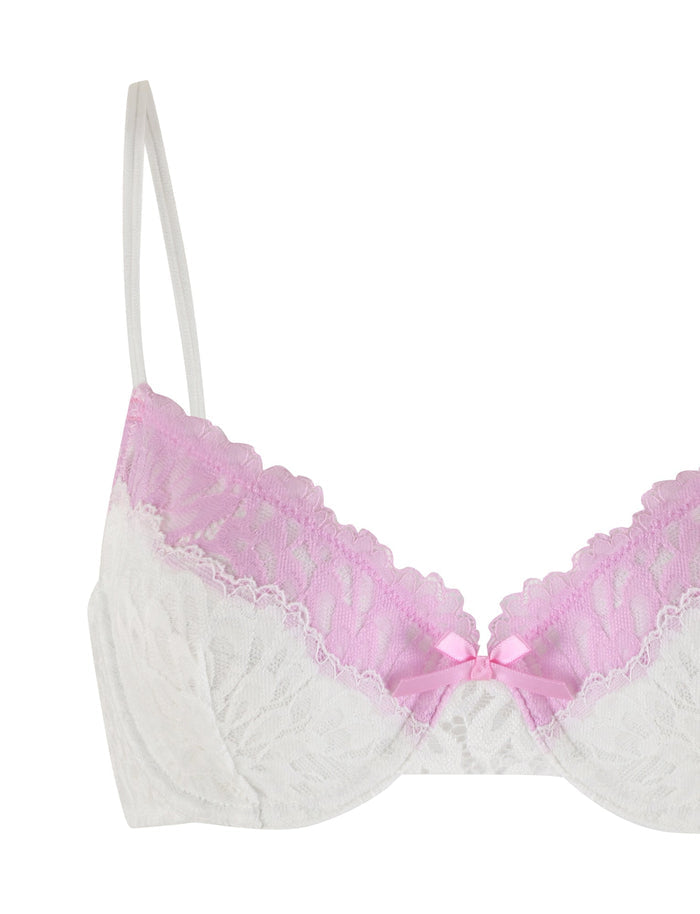 The DEVYN SET - MULTI : WHITE/ PINK from TIGERMIST is pictured. This delicate pink lace bra features light pink lace trim along the top edge of the cups and is covered in white lace. It includes thin white adjustable shoulder straps and a small pink ribbon bow at the center front, completing the look.