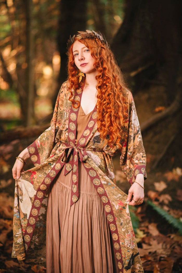 Model wearing Dreamweaver Opera Duster – featuring Alphonse Mucha’s zodiac woman, celestial crown, and burgundy zodiac trim inspired by 1970s luxe bohemian style – Market of Stars.