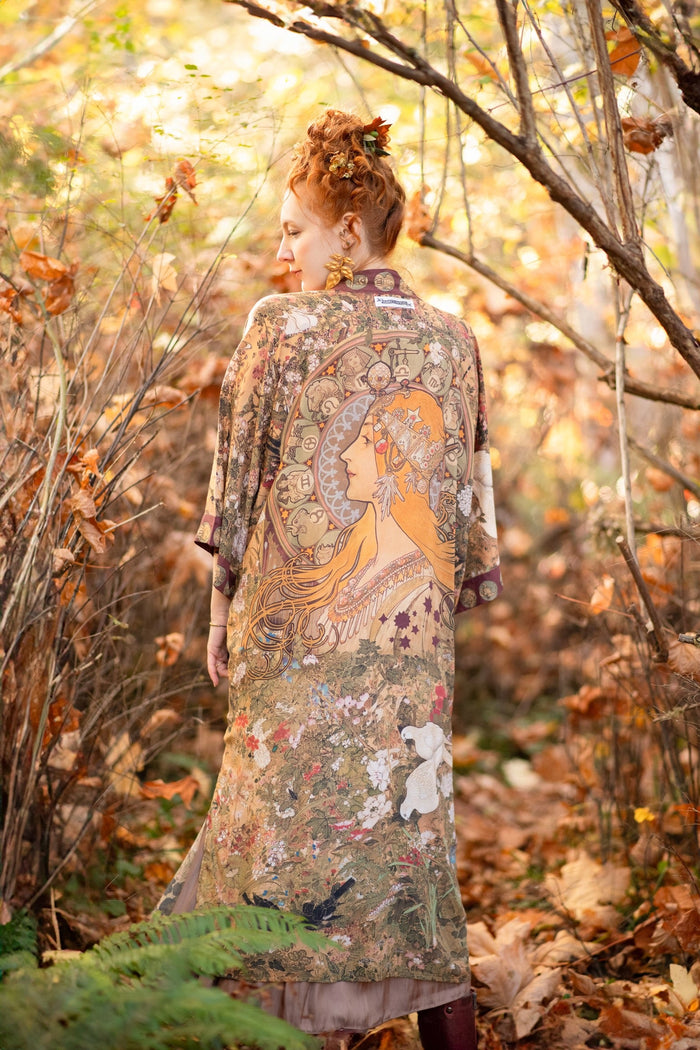 Model wearing Dreamweaver Opera Duster – featuring Alphonse Mucha’s zodiac woman, celestial crown, and burgundy zodiac trim inspired by 1970s luxe bohemian style – Market of Stars.