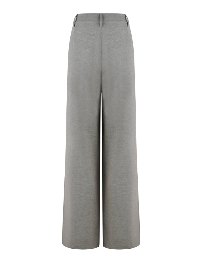 An image of the EMALINE PANT - GREY by TIGERMIST. The pair of grey wide-leg suit pants feature a high-waisted, tailored fit with belt loops at the waistband and a simple, clean design. They appear to be made from smooth fabric, giving an elegant appearance.