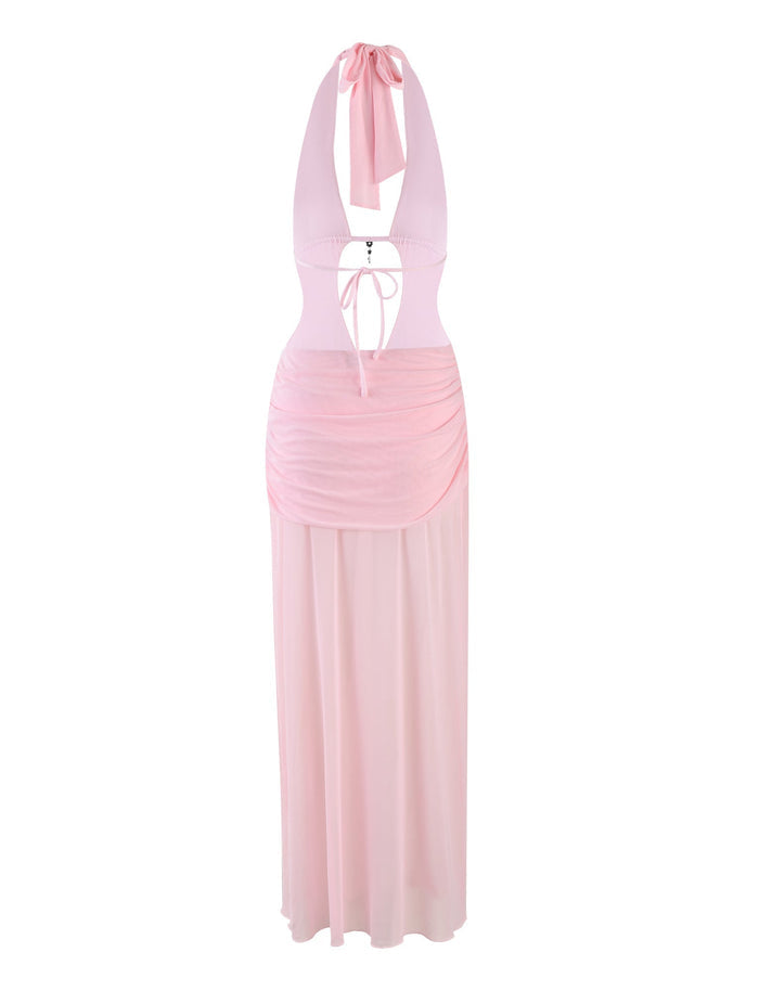 The ESHA MAXI DRESS - PINK: BABY PINK by TIGERMIST is a light pink halter neck maxi dress with a plunging neckline, keyhole bodice, and ruched waist. It features sheer, flowing fabric from the waist downward, adding a delicate and elegant touch.