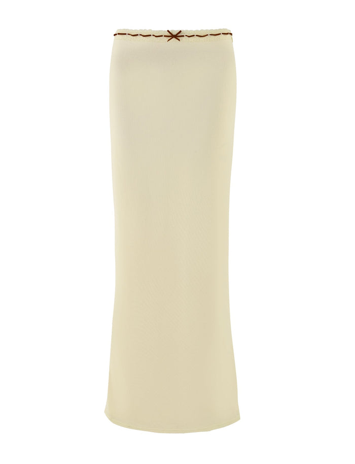 Introducing the FENNEL SKIRT by TIGERMIST in a pale yellow hue. This long, tube-style skirt boasts a simple yet elegant design, featuring a decorative bow at the top edge and delicate lace trim for added charm. Its smooth texture and straight silhouette complete the minimalistic look.