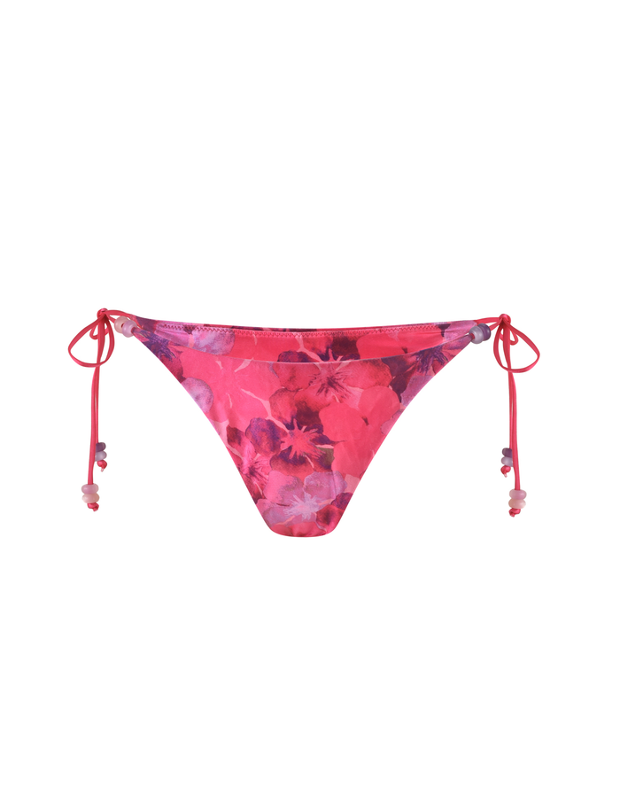 The TIGERMIST FINLEA BIKINI BOTTOM - PINK : HIBISCUS features a pink floral design with purple and red patterns, cheeky bikini cut, side ties with beaded ends, and is made from stretchy elastane fabric. Displayed on a white background.