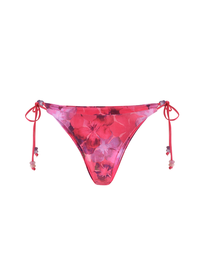 The TIGERMIST FINLEA BIKINI BOTTOM - PINK : HIBISCUS features a cheeky cut, pink and red floral print, soft elastane fabric, adjustable side tie strings with beaded ends for a minimal feminine touch.