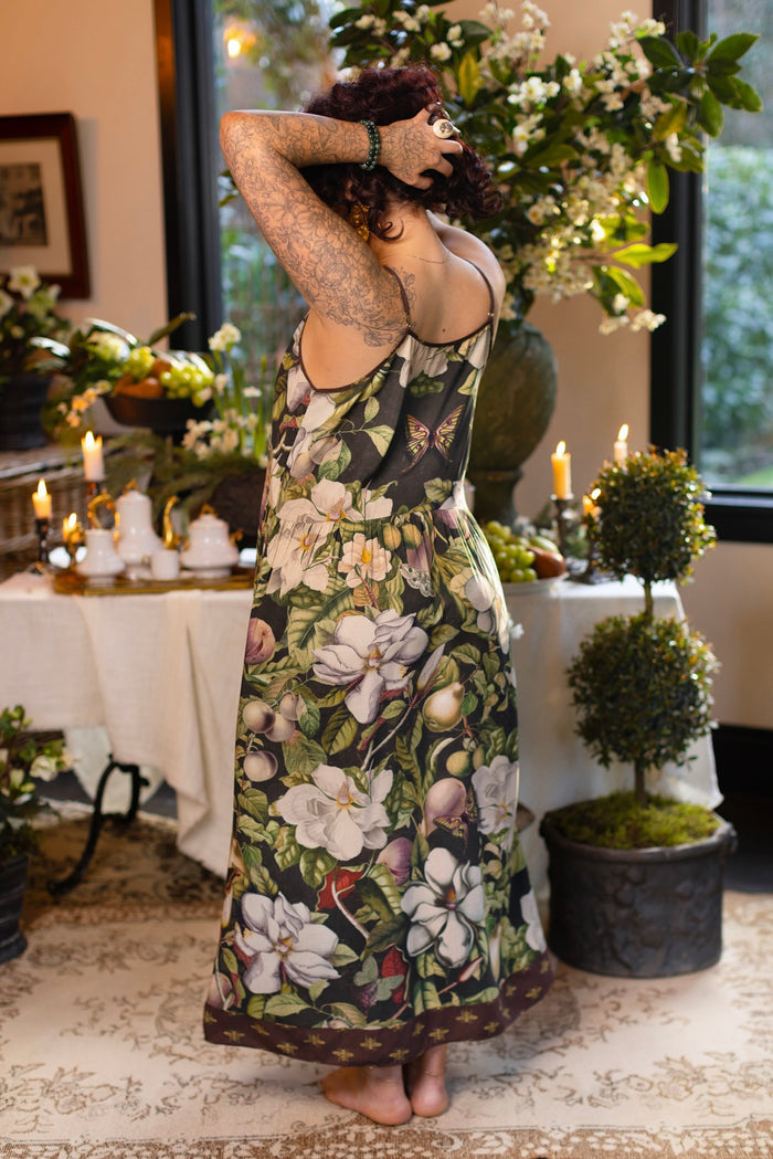 Model wearing a maxi-length slip dress featuring vintage magnolia lithographs, delicate moth etchings, and charming bumblebee trim - Market of Stars