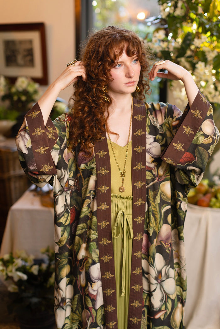 Model wearing a full length kimono duster robe featuring vintage magnolia lithographs, delicate moth etchings, and charming bumblebee trim - Market of Stars