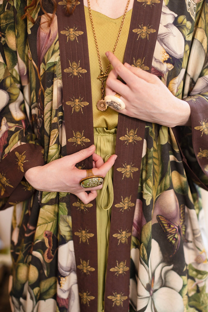 Model wearing a full length kimono duster robe featuring vintage magnolia lithographs, delicate moth etchings, and charming bumblebee trim - Market of Stars