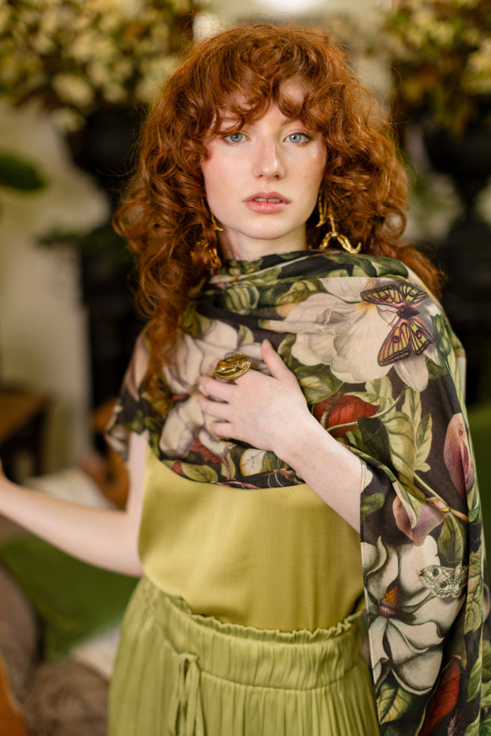 Model wearing a lightweight bamboo viscose scarf featuring vintage magnolia lithographs, delicate moth etchings and charming bumblebee trim - Market of Stars