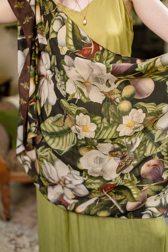 Model wearing a lightweight bamboo viscose scarf featuring vintage magnolia lithographs, delicate moth etchings and charming bumblebee trim - Market of Stars