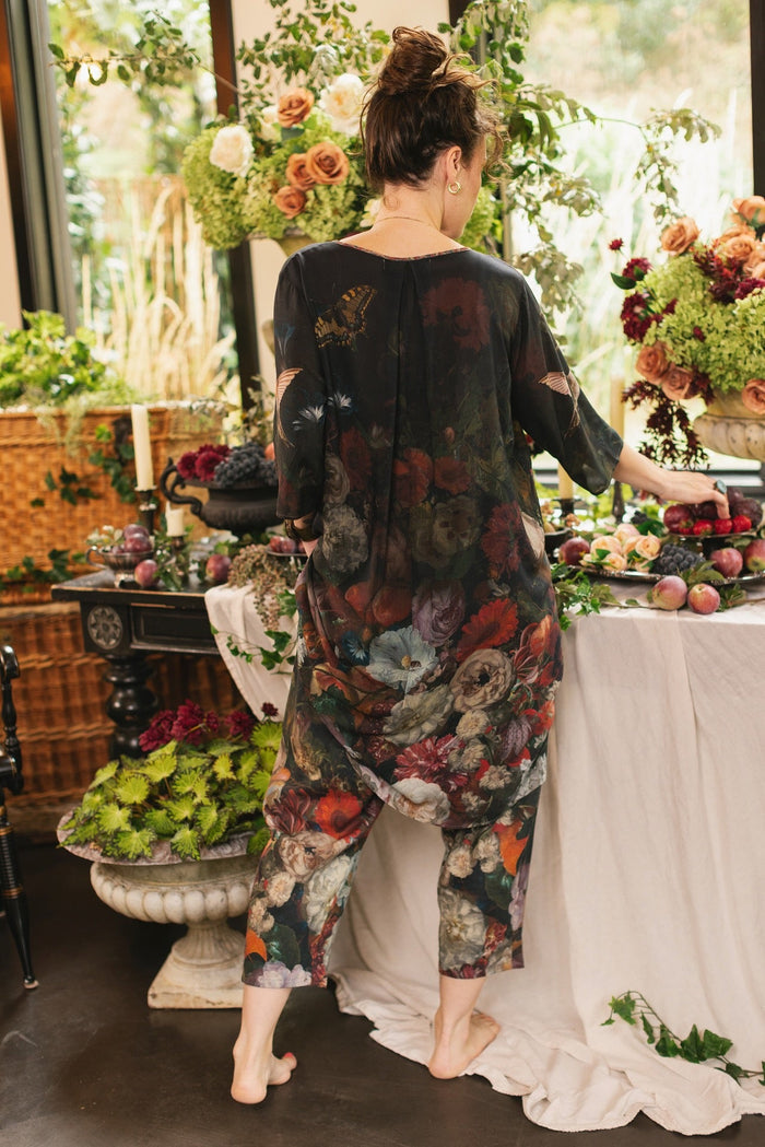 Model wearing the Flight of Fancy Artist Dress featuring vintage floral paintings and a bouquet of hummingbirds symbolizing hope and joy – Market of Stars.