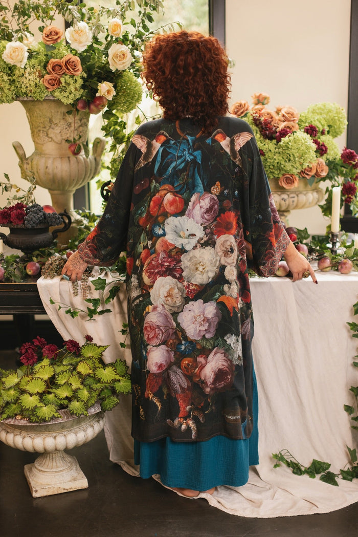 Model showcasing the Flight of Fancy Opera Robe featuring vibrant hummingbirds and historic floral paintings by Rachel Ruysch – Market of Stars.