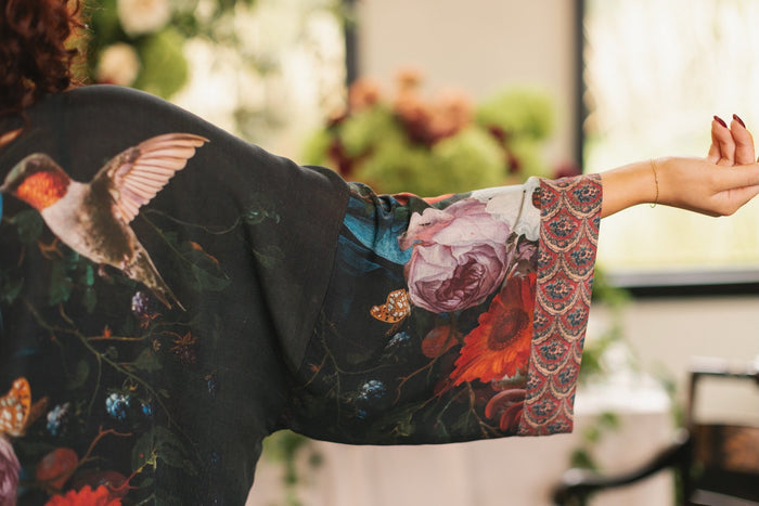 Model showcasing the Flight of Fancy Opera Robe featuring vibrant hummingbirds and historic floral paintings by Rachel Ruysch – Market of Stars.